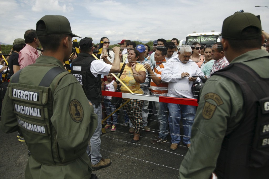 People wait to try to cross the Simon Bolivar international bridge in front of Venezuelan soldiers on the border with Colombia, at San Antonio in Tachira state, Venezuela, August 22, 2015. Venezuela's closure of two border crossings with Colombia hurts innocent people, Colombia's President Juan Manuel Santos said on Saturday, adding that he hoped to speak to his Venezuelan counterpart Nicolas Maduro to find a solution. Maduro closed the crossings on Wednesday after a shootout between smugglers and troops left three soldiers wounded. He declared a 60-day state of emergency in five border municipalities on Friday. REUTERS/Carlos Eduardo Ramirez