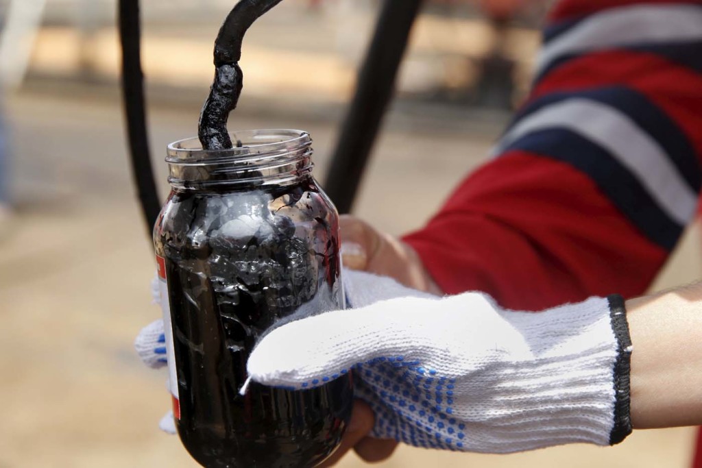 Oilfield workers collect a crude oil sample at an oil well operated by Venezuela's state oil company PDVSA, in the oil rich Orinoco belt, near Morichal at the state of Monagas April 16, 2015. Venezuela has launched talks this month on a novel plan to blend the country's heavy crude with light oil from other OPEC allies, seeking to create a new variety that can compete against swelling U.S. and Canadian supplies. The proposal, which would expand on a pilot scheme involving Algerian oil last year, envisions supplying refineries built for medium-grade crudes rather than the light oil that has become plentiful as a result of the North American shale boom, said the head of state oil company PDVSA, Eulogio del Pino. Picture taken on April 16, 2015. REUTERS/Carlos Garcia Rawlins
